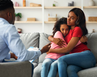 mother and daughter hug each other while psychiatrist talking