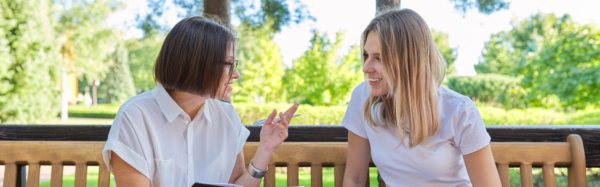 Woman social worker talking to girl teenager writing interviews in notebook